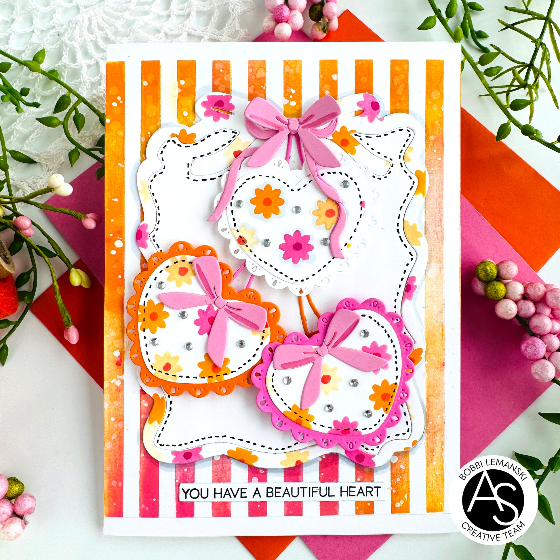 Card with decorative hearts and pink bows on a striped background, featuring the Alex Syberia Designs medallions die set. Cardmaking ideas.